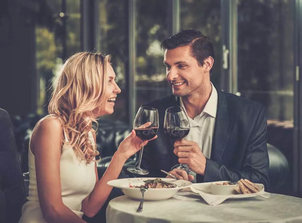 Happy couple in a restaurant with glasses of red wine.